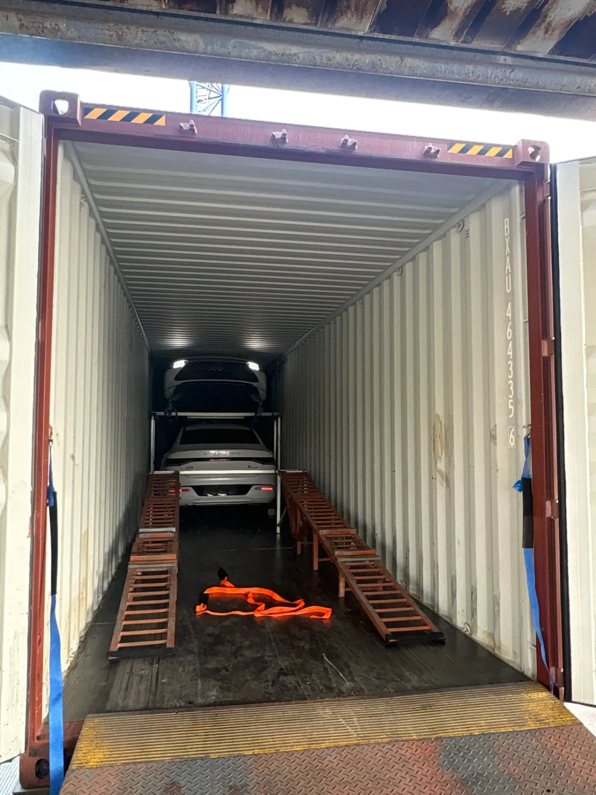 Two vehicles secured on a two-tier rack inside a Sino Gear export container